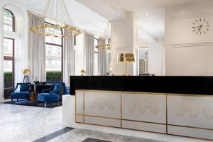 a lobby with a reception desk and blue chairs at Hotel Bristol, A Luxury Collection Hotel, Warsaw in Warsaw