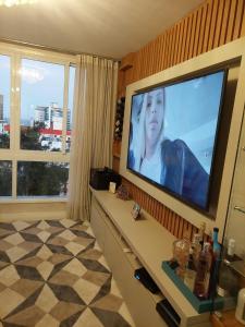 ein Wohnzimmer mit einem Flachbildfernseher an der Wand in der Unterkunft Belo Apartamento no Centro de Capão da Canoa in Capão da Canoa