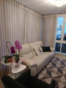 ein Wohnzimmer mit einem weißen Sofa und einem Tisch mit Blumen in der Unterkunft Belo Apartamento no Centro de Capão da Canoa in Capão da Canoa