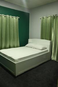 a white bed in a room with green walls at Augi's Rental in Onverwacht