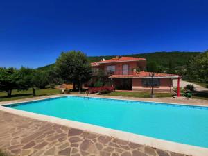 a large blue swimming pool in front of a house at Villa Montesegnale in Bolsena