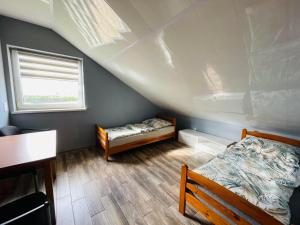 a attic room with two beds and a window at Kwatera - Pod Wiatrakiem, JACUZZI ZEWNĘTRZNE in Czarna