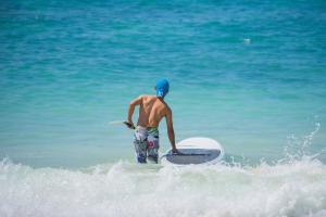 a man standing in the ocean with a surfboard at Phuket Marriott Resort & Spa, Merlin Beach in Patong Beach