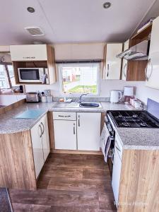 eine Küche mit weißen Schränken und einem Herd mit Backofen in der Unterkunft Summer Breeze in Perranzabuloe