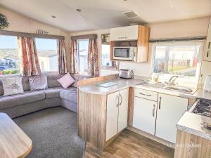 eine Wohnwagen-Küche und ein Wohnzimmer mit einem Sofa in der Unterkunft Summer Breeze in Perranzabuloe