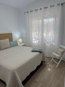 a bedroom with a bed and a chair and a window at Chalets Paraíso Playa de Mazagón Con Vistas al Mar in Mazagón