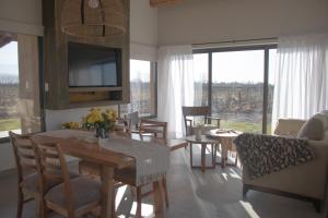 Una sala de estar con una mesa y sillas y un televisor. en Las Nencias Houses, en San Carlos