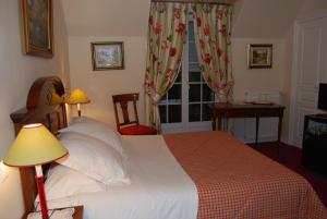 a bedroom with a bed and a desk and a window at Hostellerie de la Motte jean in Saint-Coulomb
