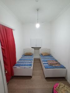 2 camas en una habitación pequeña con cortina roja en Happy Day, en Telavi