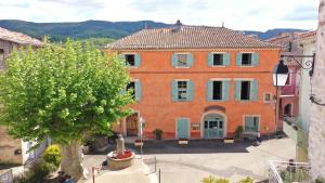 a large orange building with a tree in front of it at Des Lits Sur La Place in Hérépian