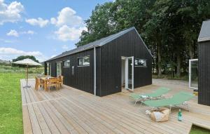 a black house with a deck with a table and chairs at 4 Bedroom Nice Home In Ebeltoft in Ebeltoft +17 photos