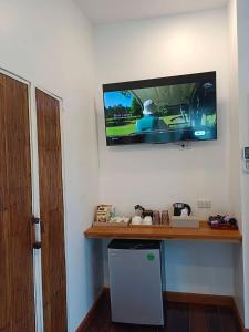 a television hanging on a wall with a dishwasher at Nangyuan Island Dive Resort in Ko Tao