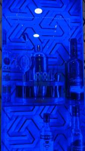 a refrigerator filled with bottles and glasses in a blue light at Auro studio home in Pūrnānkuppam