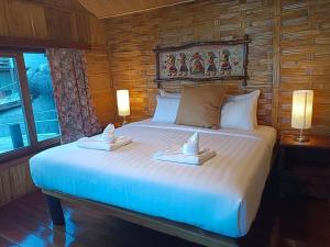 a bedroom with a large white bed with two towels at Nangyuan Island Dive Resort in Ko Tao
