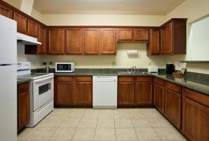 a kitchen with wooden cabinets and white appliances at ASPEN GRAND HOTEL LaPorte in La Porte