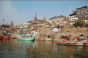 a group of boats in a body of water with buildings at Pushkarni Home Stay in Varanasi