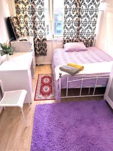 ロンドンにあるEXCELLENT DOUBLE ROOMS IN CHEAP RATE AROUND CENTRAL LONDONの紫色のベッドルーム(ベッド1台、紫色のラグ付)