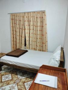 Bett in einem Zimmer mit einem Schreibtisch und einem Fenster in der Unterkunft Hill garden homestay,Vagamon in Vagamon