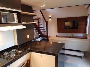 a kitchen with a stove and a sink and a microwave at Casa Bonfim - Excelente opção no centro de Arraial in Porto Seguro