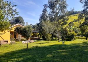a house in a field with trees and a hill at Recanto Sol Maior - Casa Girassol in Sapucaí-Mirim