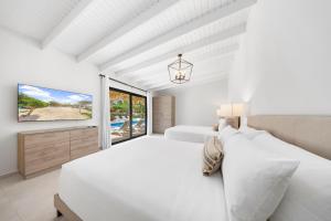 Un dormitorio blanco con dos camas y un televisor. en Boca Beach House NEW LUX 6 Bed 6 Bath Pool Walk To Beach, en Palm-Eagle Beach