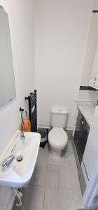 a white bathroom with a toilet and a sink at Cosy Central 2 En-suite Bedrooms Apartment in Hastings +9 photos