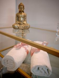 a buddha statue sitting on a glass table with towels at Casa Petrí Home SPA in Palermo