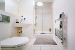 a white bathroom with a toilet and a shower at Chic property near Tower Hill with a gym in London +31 photos