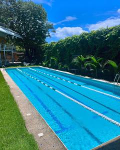 a large blue swimming pool with trees in the background at Hotel Tama Lodge in Tamarindo