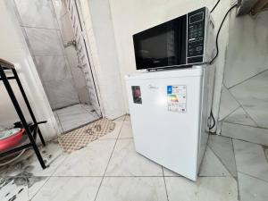 un forno a microonde seduto sopra un frigorifero di Ap próximo ao Arco com garagem e ar sem TV a Sobral
