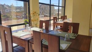 ein Restaurant mit Holztischen und -stühlen und einem großen Fenster in der Unterkunft Hôtel Évasion in Fianarantsoa