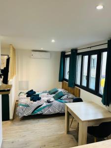 a bedroom with a bed and a table and windows at Charmant studio en centre-ville in Céret