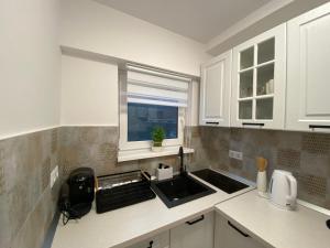 a kitchen with white cabinets and a sink and a window at M & A Accommodation in Topliţa