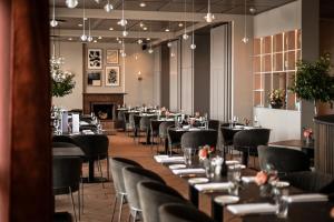 a dining room with tables and chairs and a fireplace at Golfhotel & Restaurant Lindenhof in Bad Vilbel