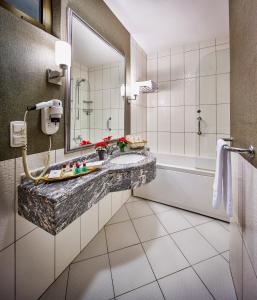 ein Badezimmer mit einem Waschbecken, einer Badewanne und einem Spiegel in der Unterkunft Güneş Hotel Merter in Istanbul