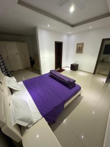 una camera con letto e lenzuola viola e bianche di Villa Somone a Dakar Altre 16 foto