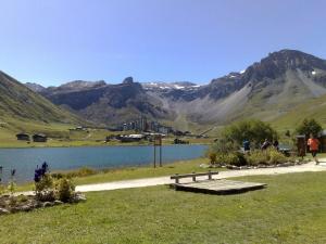 a bench next to a lake with mountains in the background at Studio 20 Les Grandes Platières in Tignes