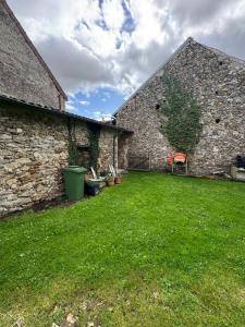 Saint-Denis-lès-RebaisにあるLe 41 - Maison PMR - Proche Disneyの緑の芝生のある古い石造りの建物の中庭