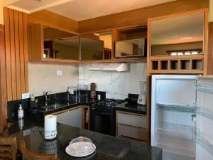 una cocina con encimeras negras y armarios de madera en Apartamentos Flat Maria, en Lençóis