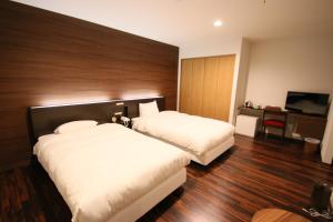 a hotel room with two beds and a television at Furano Shiyuirin in Kami-furano