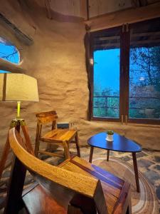 Habitación con silla, mesa y ventanas en Janki's Commune - An Earthen Stay Amidst Old Manali, en Manali