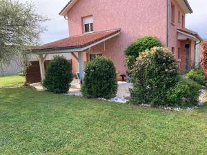 a pink house with bushes in front of a yard at Vacances et travail in Serrières-de-Briord