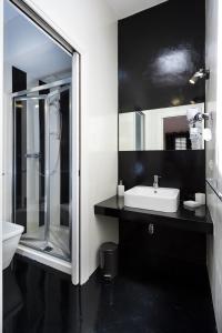 y baño blanco y negro con lavabo y ducha. en Via Nuova, en Castellammare del Golfo