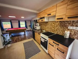 a kitchen with wooden cabinets and a bed in the background at Szőlőszem Vendégházak in Szőlősgyörök