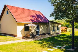 a house with a red roof and a table and chairs at Szőlőszem Vendégházak in Szőlősgyörök