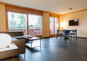 a living room with tables and chairs and a large window at Résidence Grenon in Crans-Montana