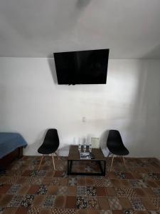 a living room with two chairs and a table and a television at Casa Arcos Tepoztlán in Tepoztlán