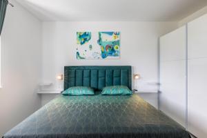 ein Schlafzimmer mit einem grünen Bett mit zwei blauen Kissen in der Unterkunft Villa Perkov private pool in Kaštela