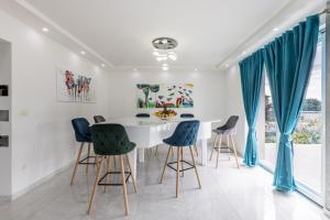 a dining room with a white table and blue chairs at Villa Perkov private pool in Kaštela