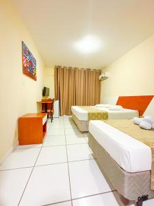 um quarto de hotel com duas camas e uma escrivaninha em Fragata Hotel em Guarapari